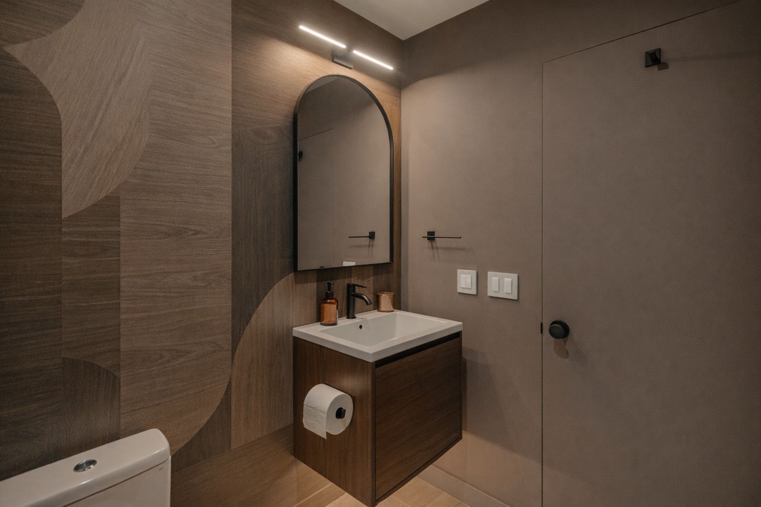 Liten kommod i mörkt trä med integrerad toalettpappershållare.